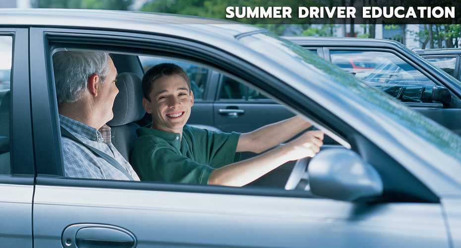 A smiling male teen driver behind the wheel and an older male adult talking to the young driver