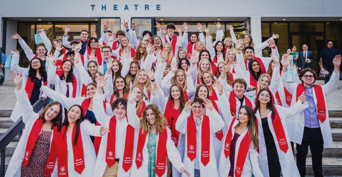 Students celebrating earning their white coats wearing red stols