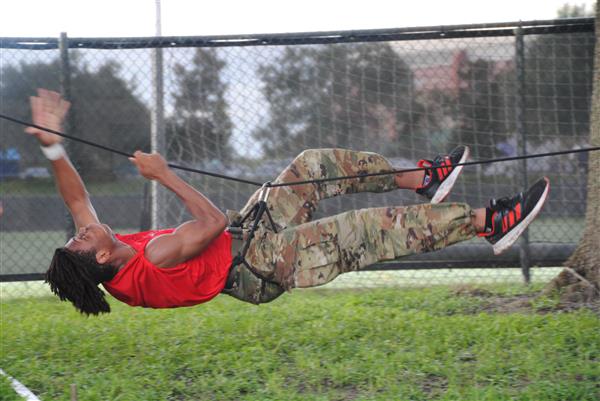 Northeast HS JROTC SAI student climbs ropes.