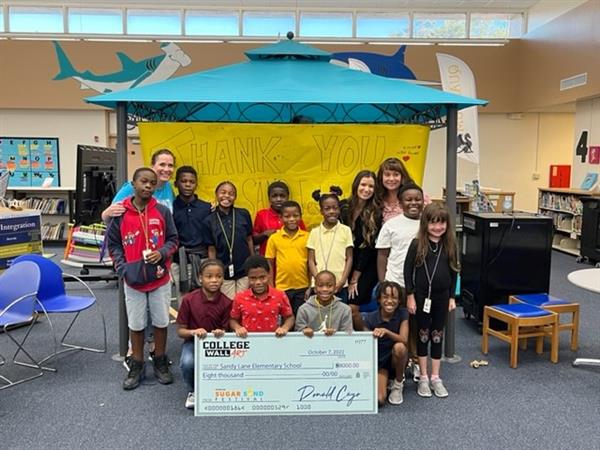 Sandy Lane Elementary Principal Kelly Austin was honored to receive a check from two representatives  of the 2022 Sugar Sand Festival. 