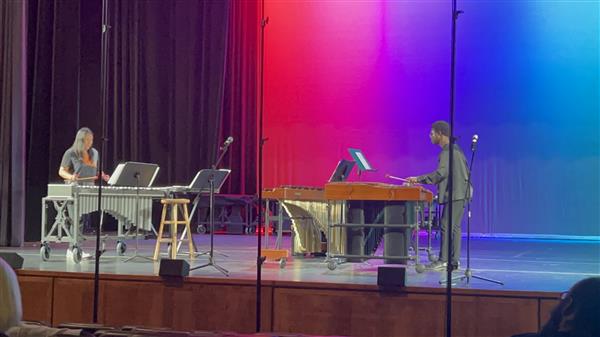 2 students play percussion instruments.