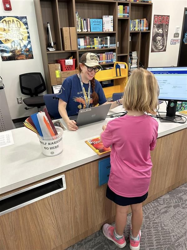 Librarian Ms. Myers Checking Out Books to Students